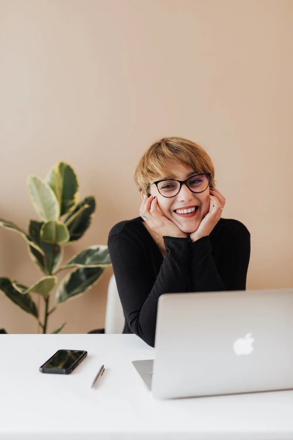 business woman at laptop with her head in her hands smiling